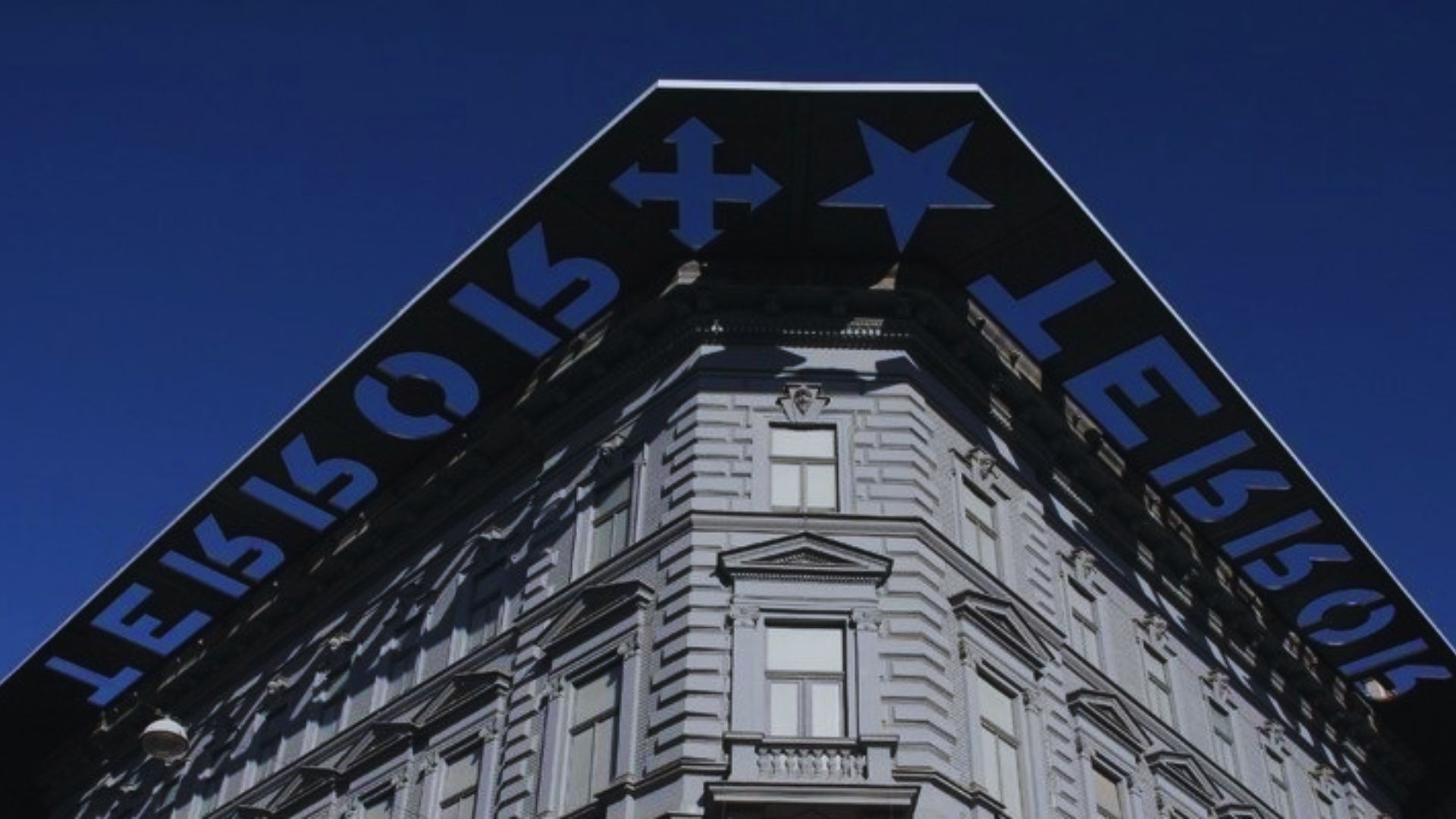 The exterior of a building with a blue sign prominently positioned on the roof.