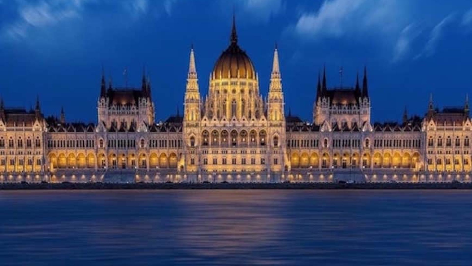 The Hungarian Parliament Building illuminated at night, showcasing its stunning architecture against a dark sky.