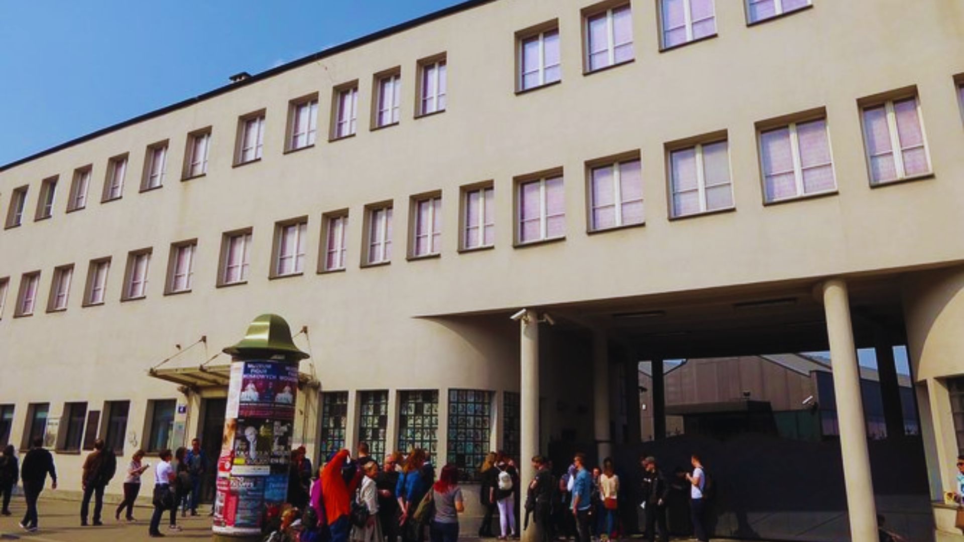 A group of people stands outside a building with a sign reading