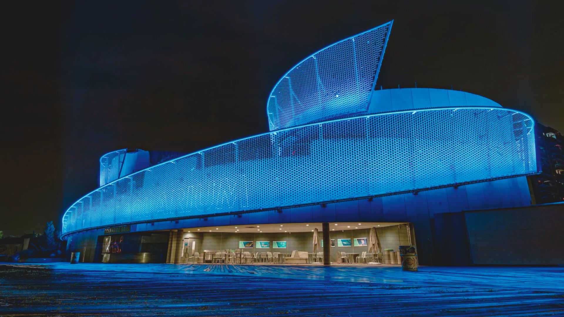 A building illuminated by blue light at night, creating a striking contrast against the dark sky.