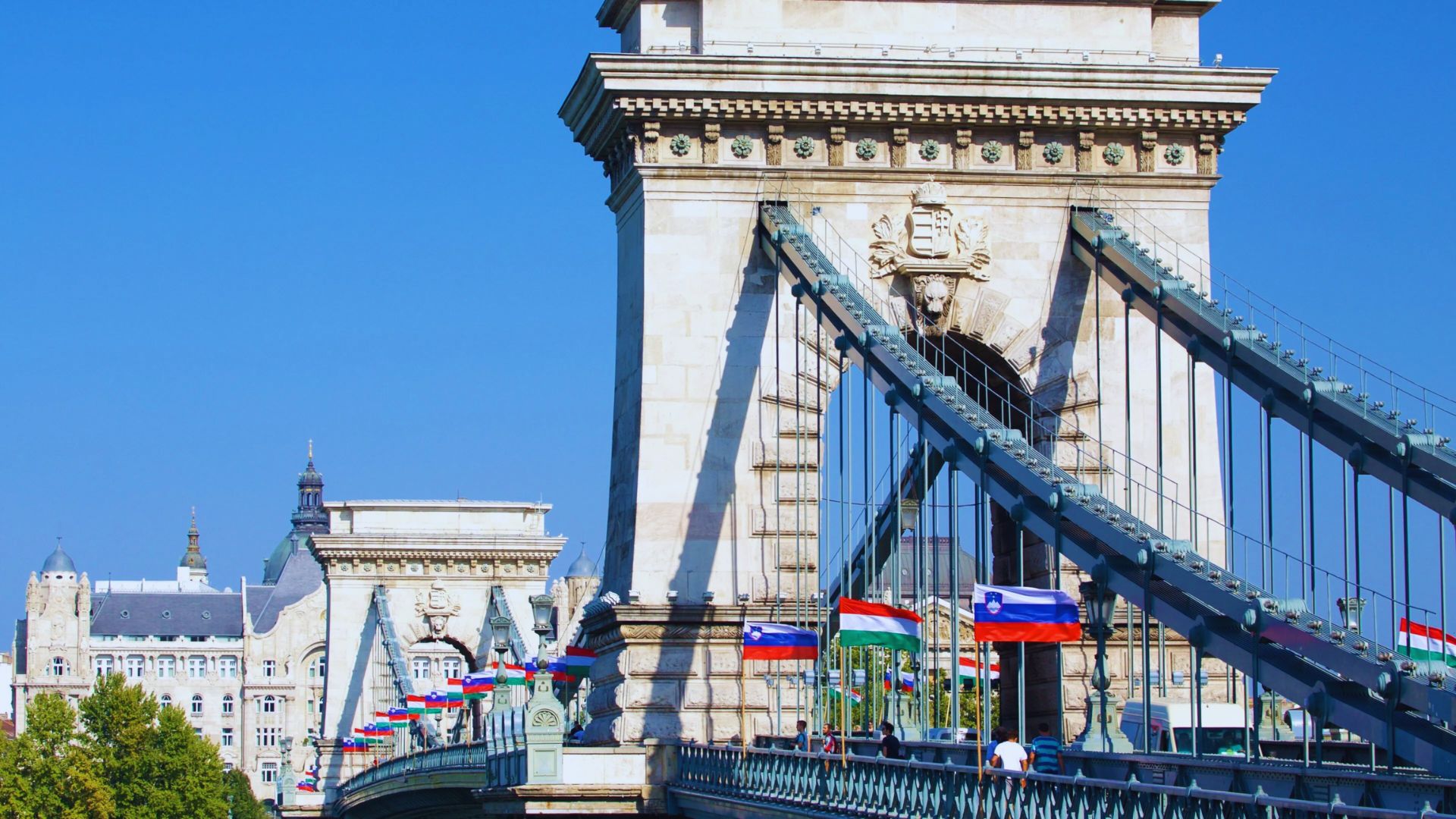 A bridge adorned with numerous flags fluttering in the wind above it.
