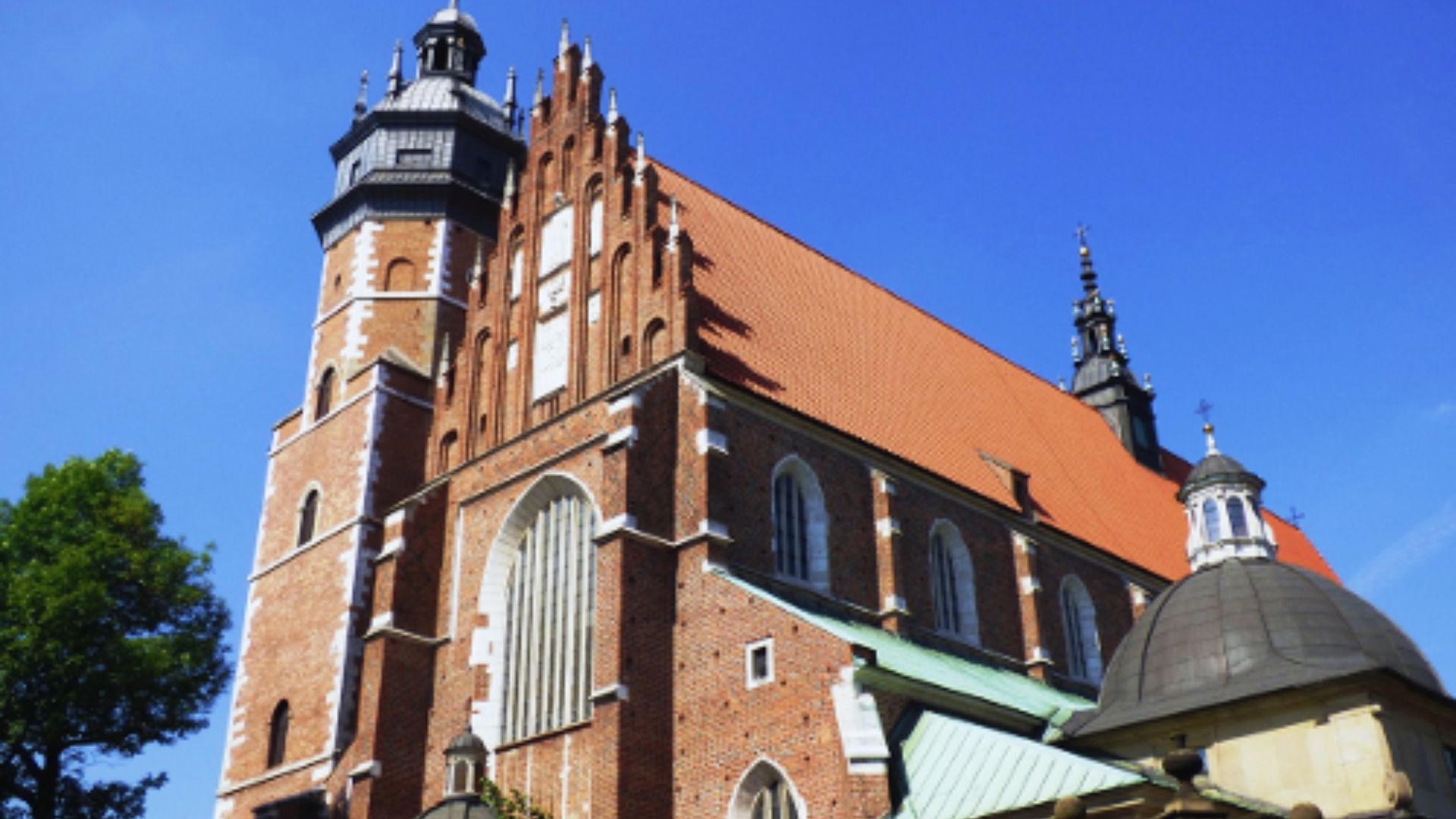 A brick church with a tall clock tower, exemplifying traditional church architecture against a clear sky.
