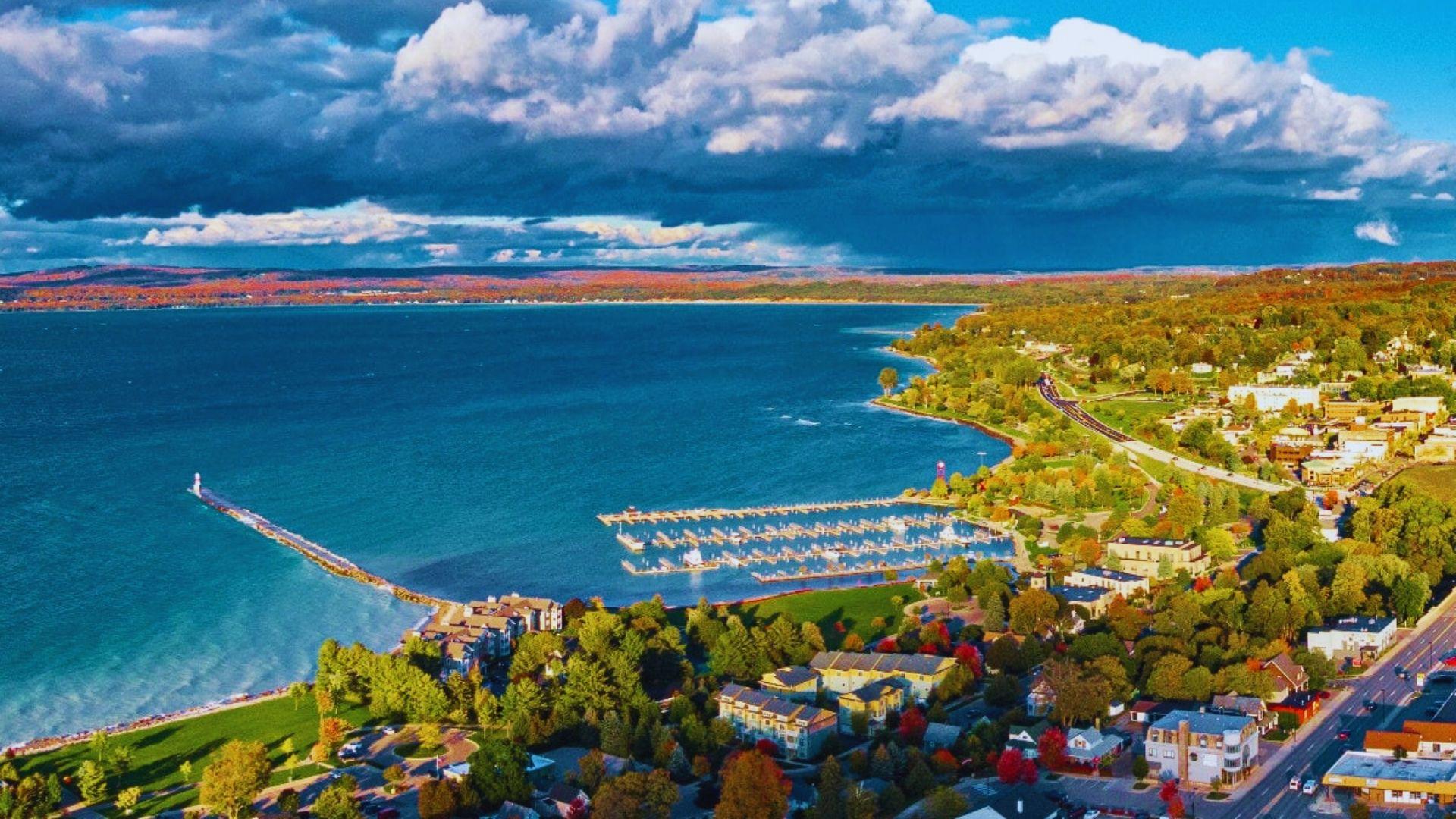Aerial view of a lakeside town, showcasing buildings and greenery along the water's edge.