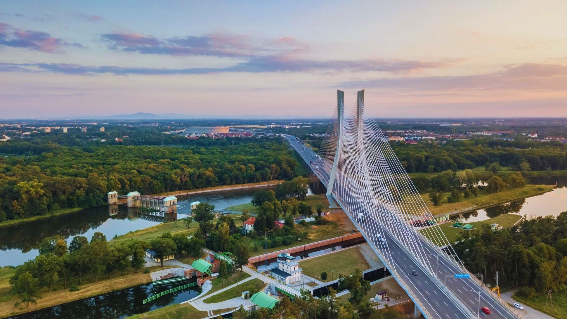 A long-span suspension bridge featuring a prominent high arch against a clear blue sky.