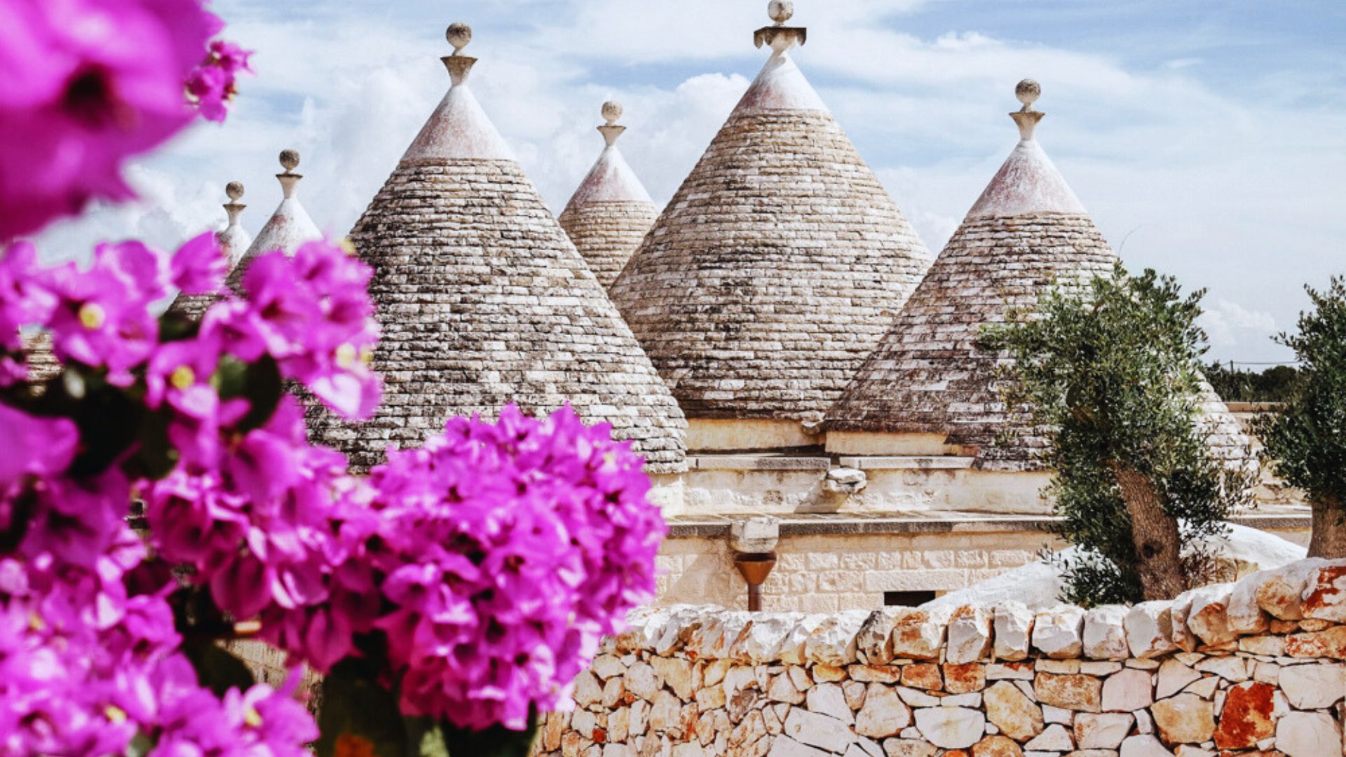 Trulli buildings in Puglia, Italy, featuring conical roofs and whitewashed stone walls, showcasing unique architectural style.