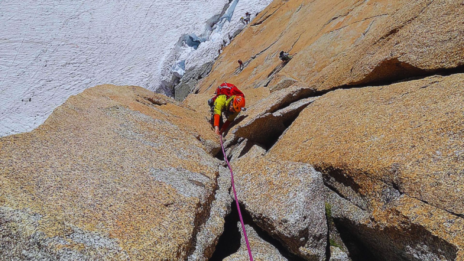 A climber ascends a rocky face, secured by a rope, showcasing determination and skill in a challenging outdoor environment.
