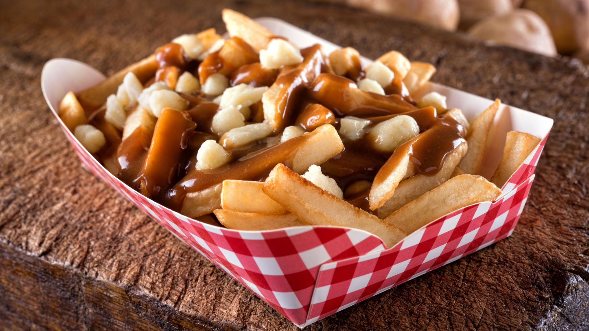 A basket of golden French fries topped with caramelized onions and rich gravy, served as a hearty comfort food dish.