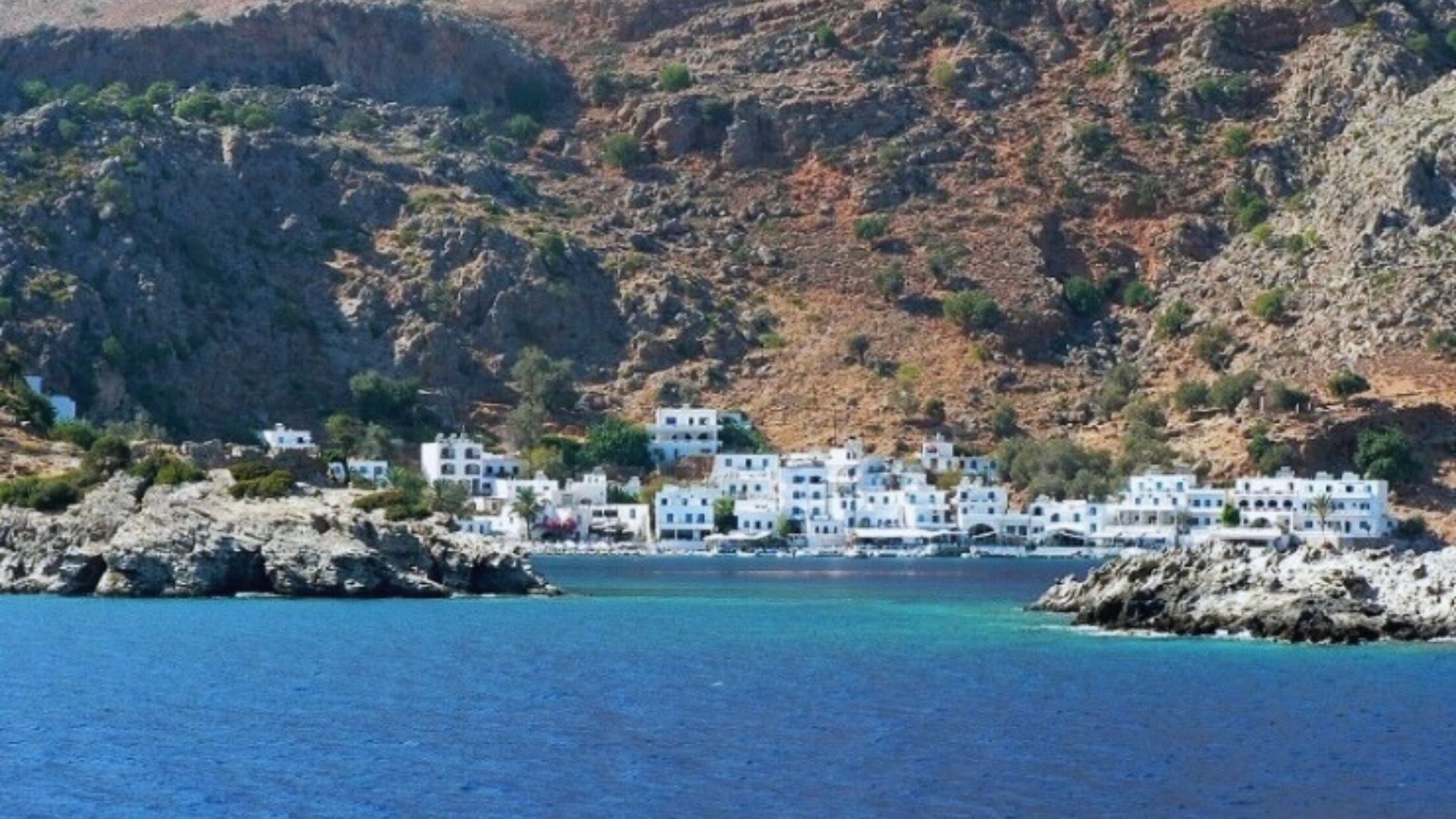 A scenic view of Kalymnos village in Greece, showcasing traditional architecture and the surrounding mountainous landscape.