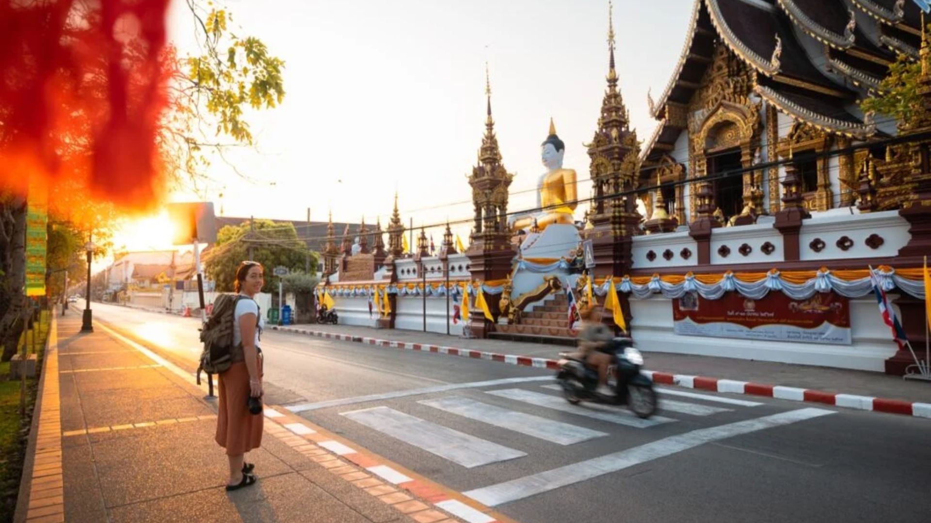 A woman walks down the street in front of a temple, showcasing the architectural details and surrounding environment.