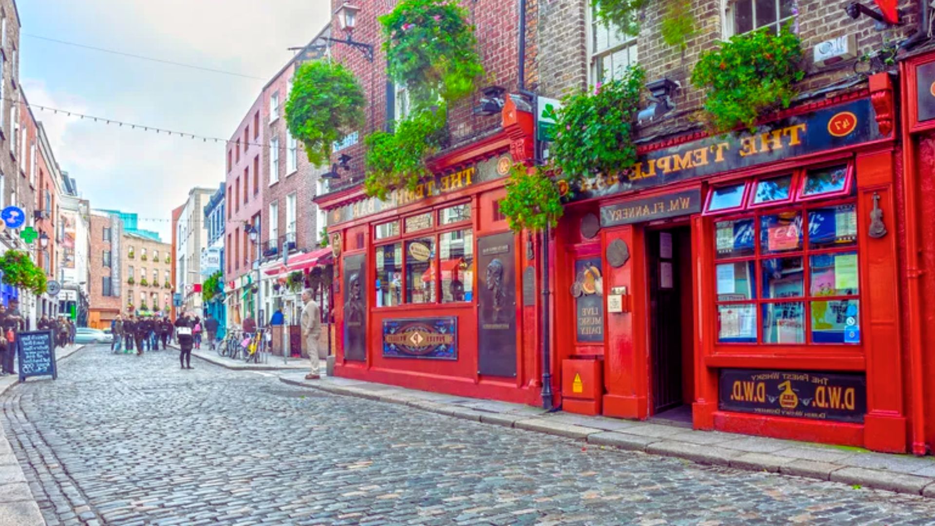 A vibrant street lined with red buildings, featuring people walking and enjoying the lively atmosphere.