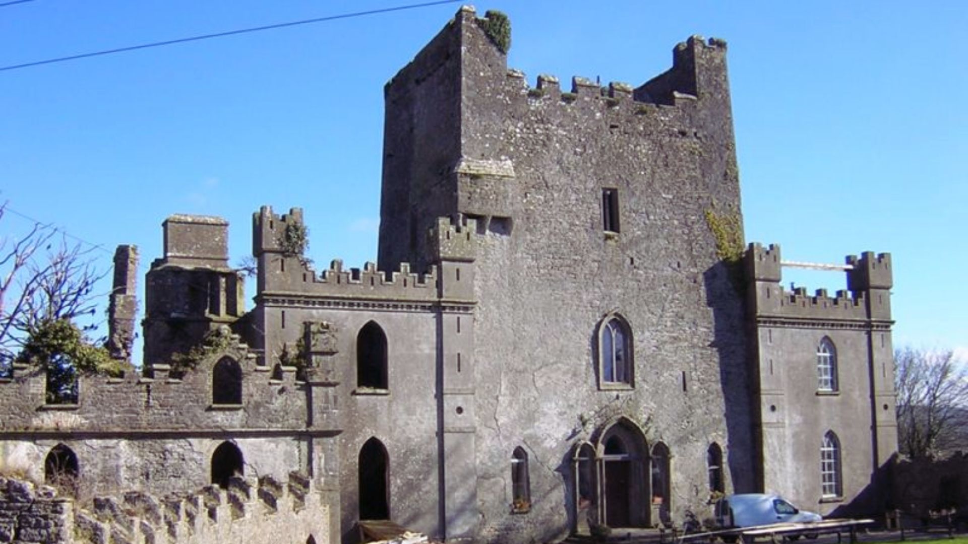 A historic stone castle with crenellated battlements and arched windows under a clear blue sky, conveying a sense of ancient strength and mystery.