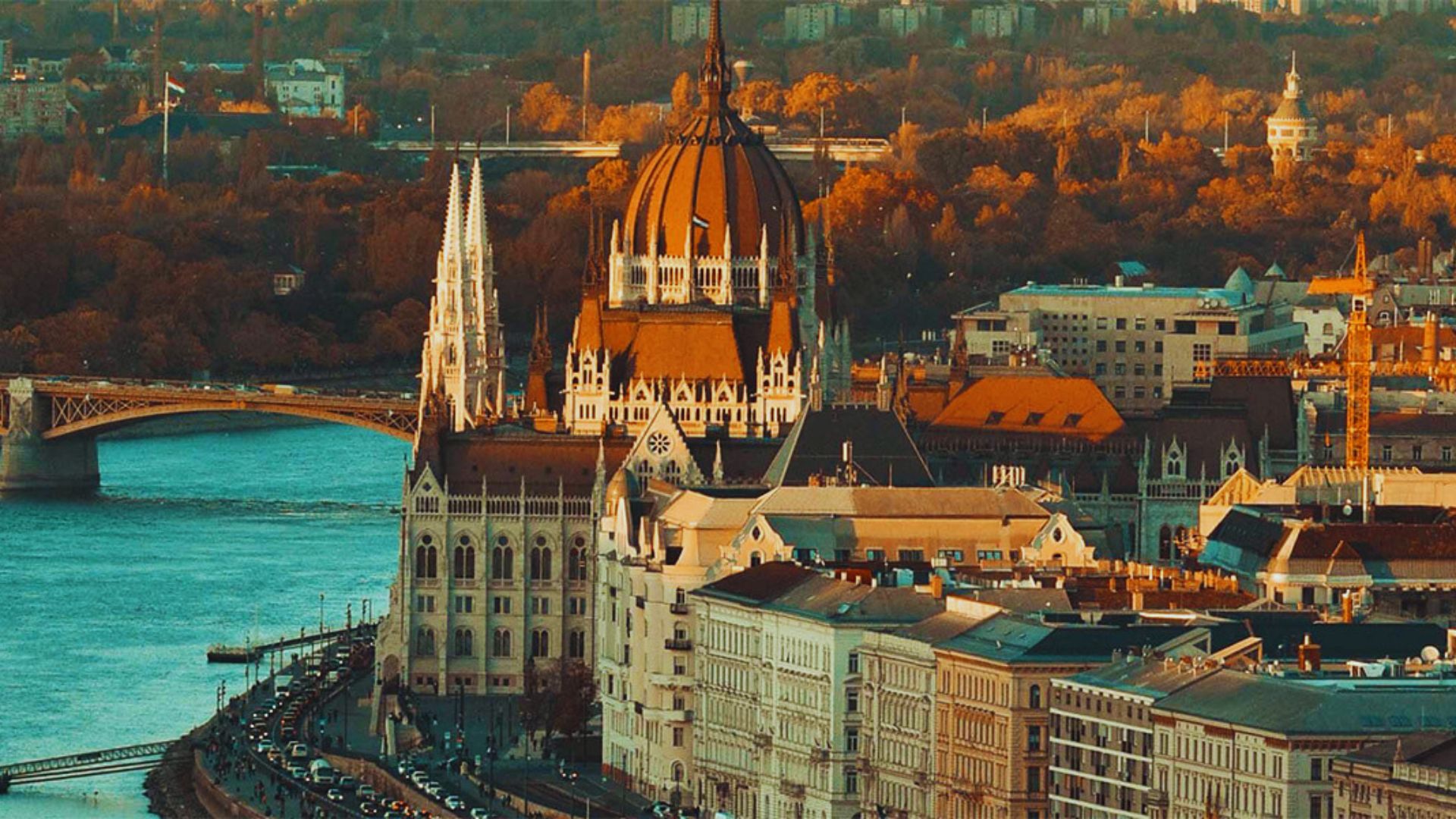 Budapest skyline featuring a prominent bridge and various historic buildings against a clear blue sky.
