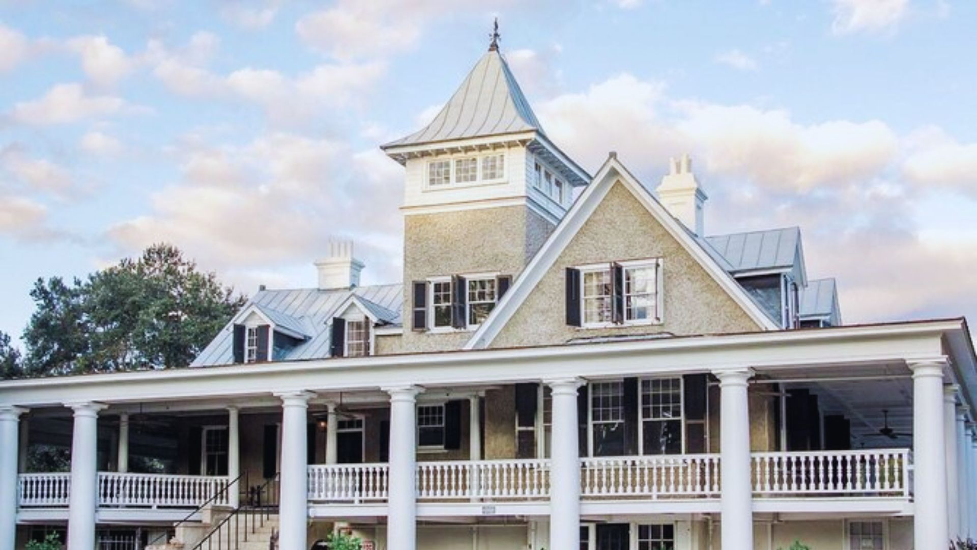 A large white house featuring a prominent steeple atop its roof against a clear blue sky.
