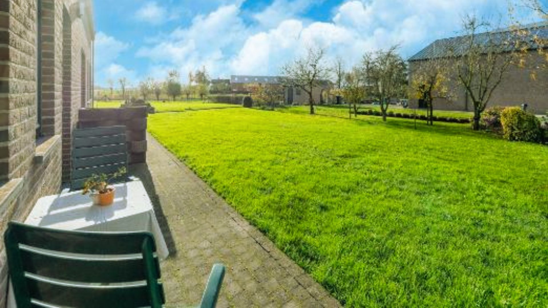 A green lawn featuring a table and chairs set up in front of a house, creating an inviting outdoor space.