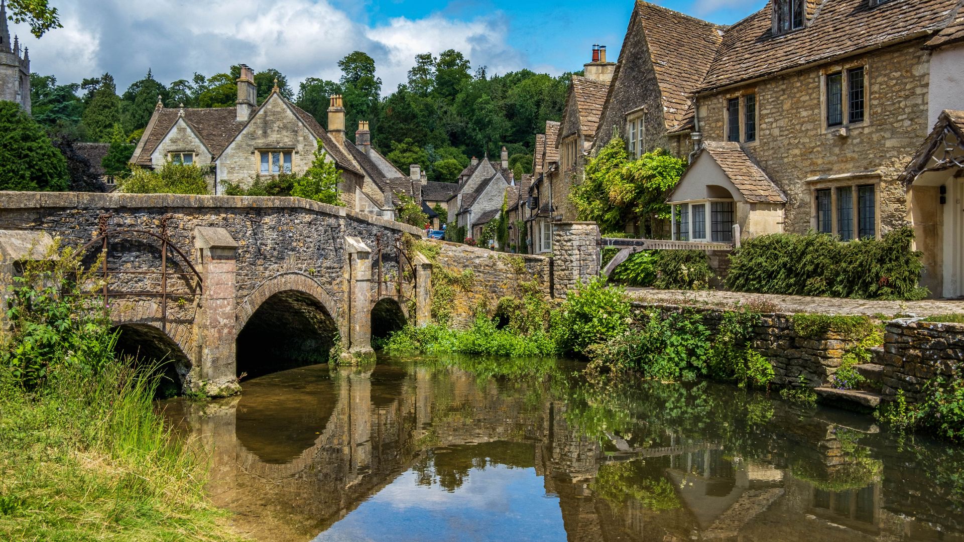 A charming house nestled in nature, featuring a tranquil stream that runs alongside it.