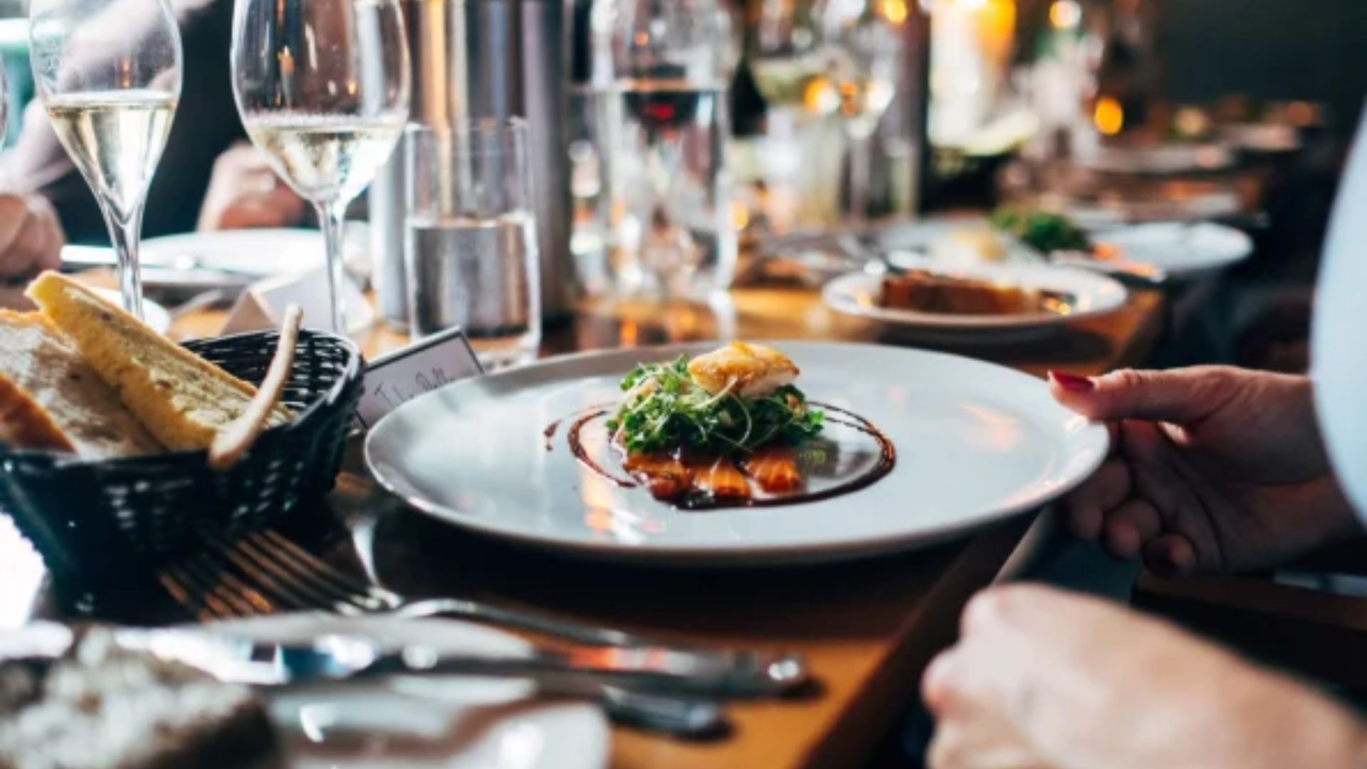 A group of people seated at a table enjoying a meal with various plates of food in front of them.