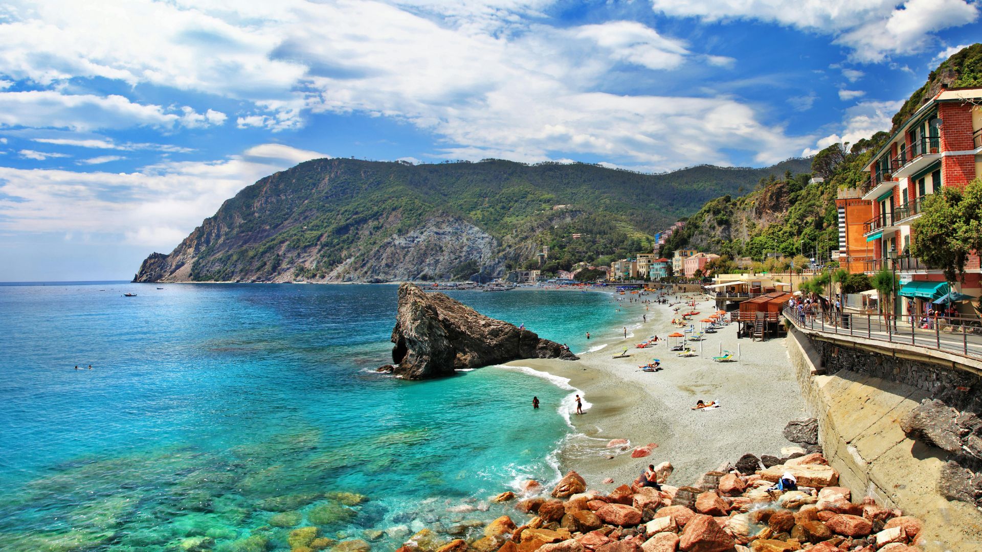 A vibrant Italian beach filled with sunbathers and beachgoers enjoying the beautiful scenery and warm weather.