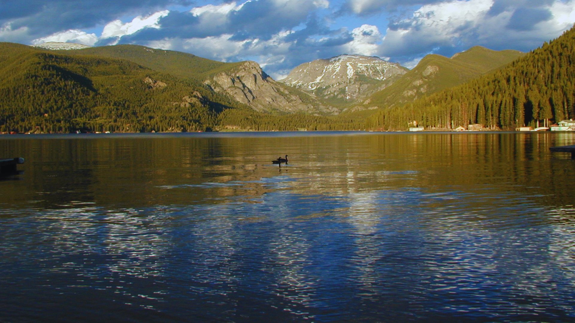 A serene lake with a small boat floating gently on its surface under a clear blue sky.