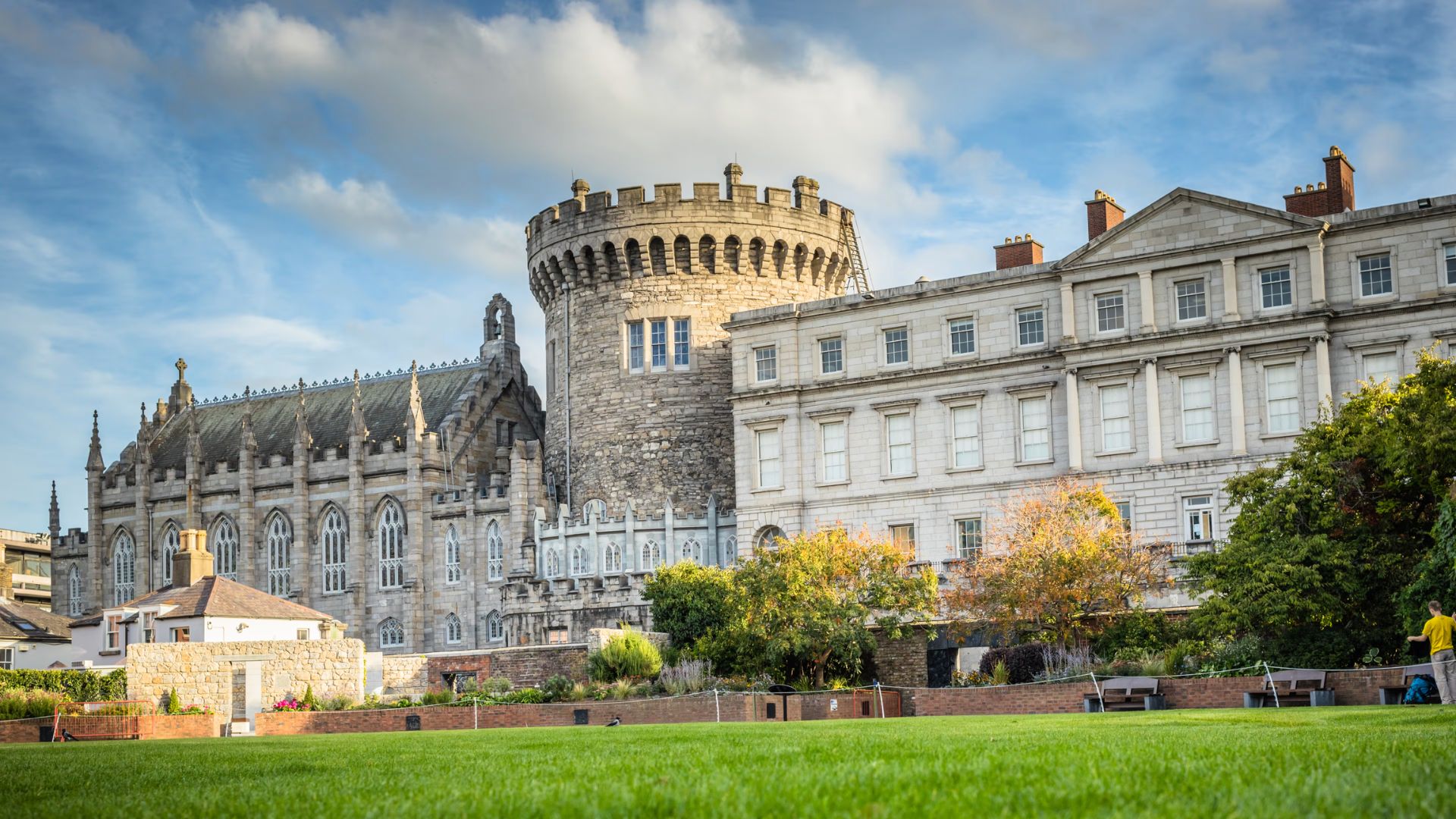 A large castle stands majestically with a lush green lawn in front, creating a picturesque landscape.