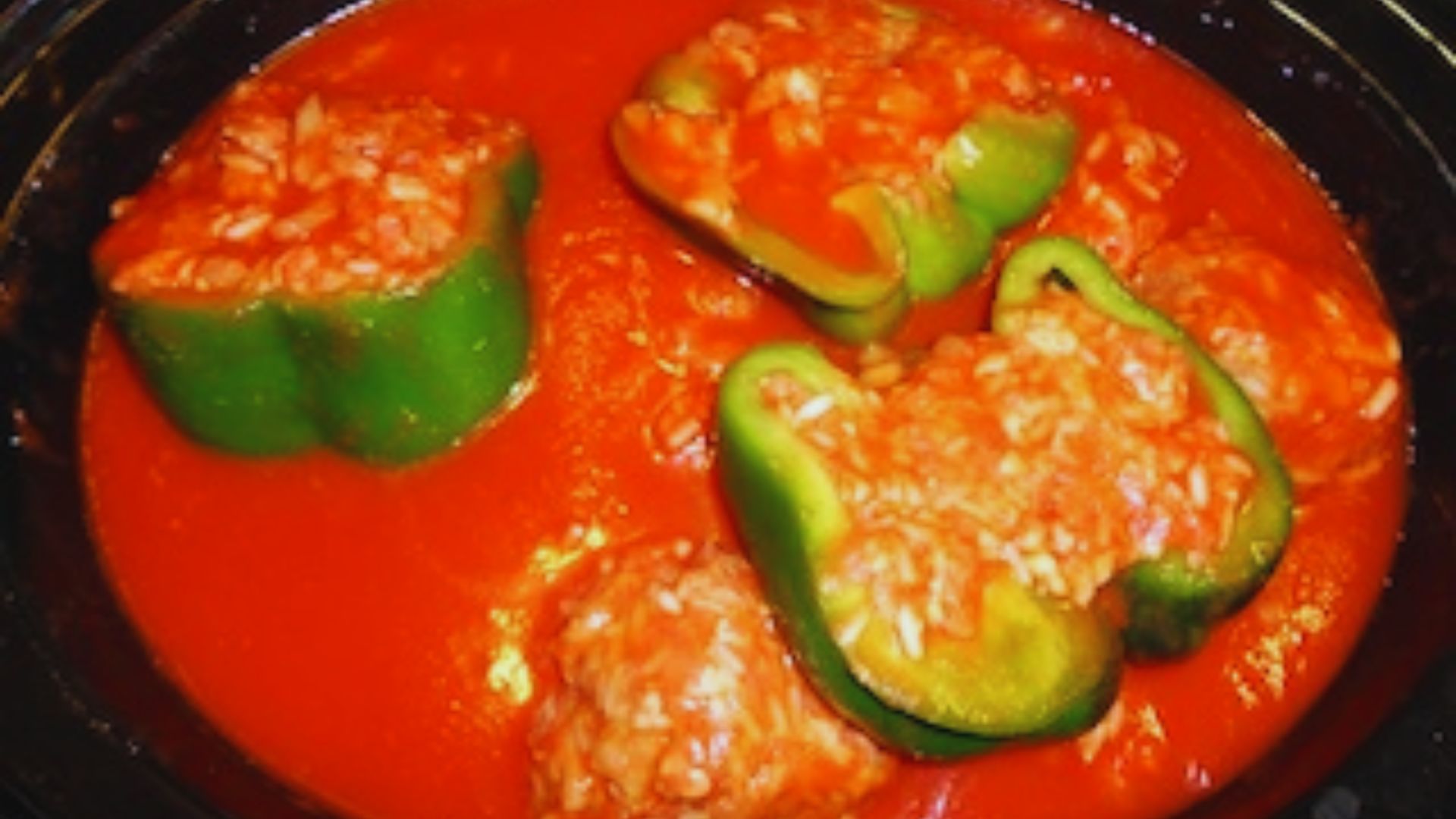 A slow cooker filled with colorful peppers and meatballs, showcasing a hearty meal preparation.