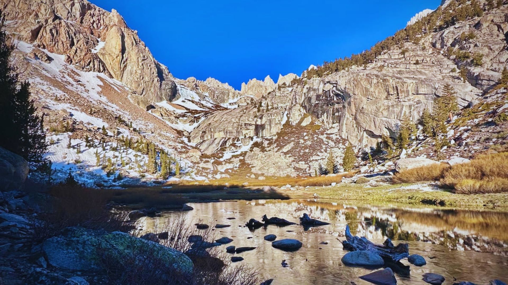 Photograph of Big Bear Lake reflecting the surrounding trees and mountains, captured by Jimmy Kirk.