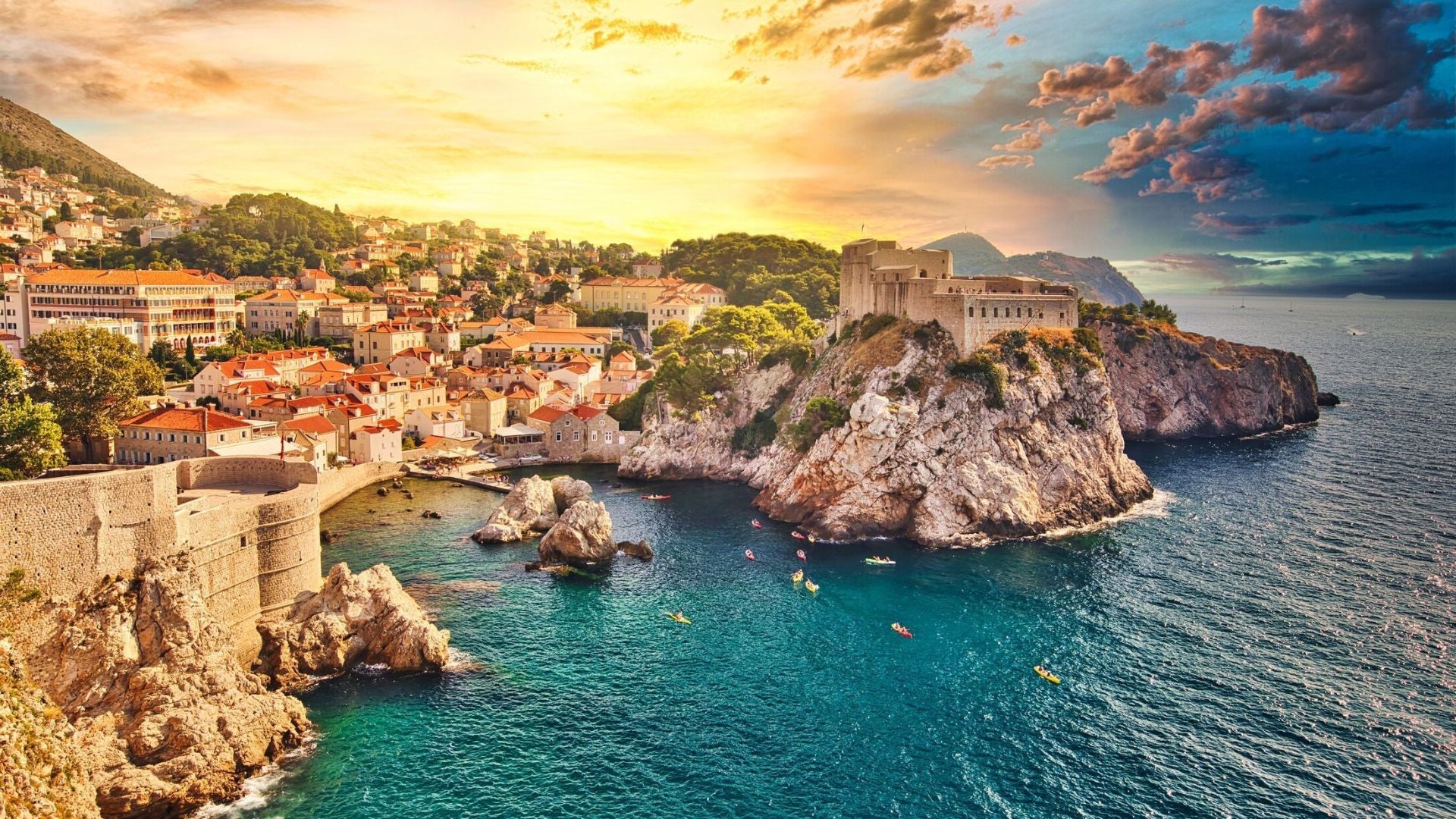 Sunset over Dubrovnik, Croatia: Aerial view of the historic city with orange rooftops, rugged cliffs, and sparkling blue Adriatic Sea, exuding warmth and tranquility.