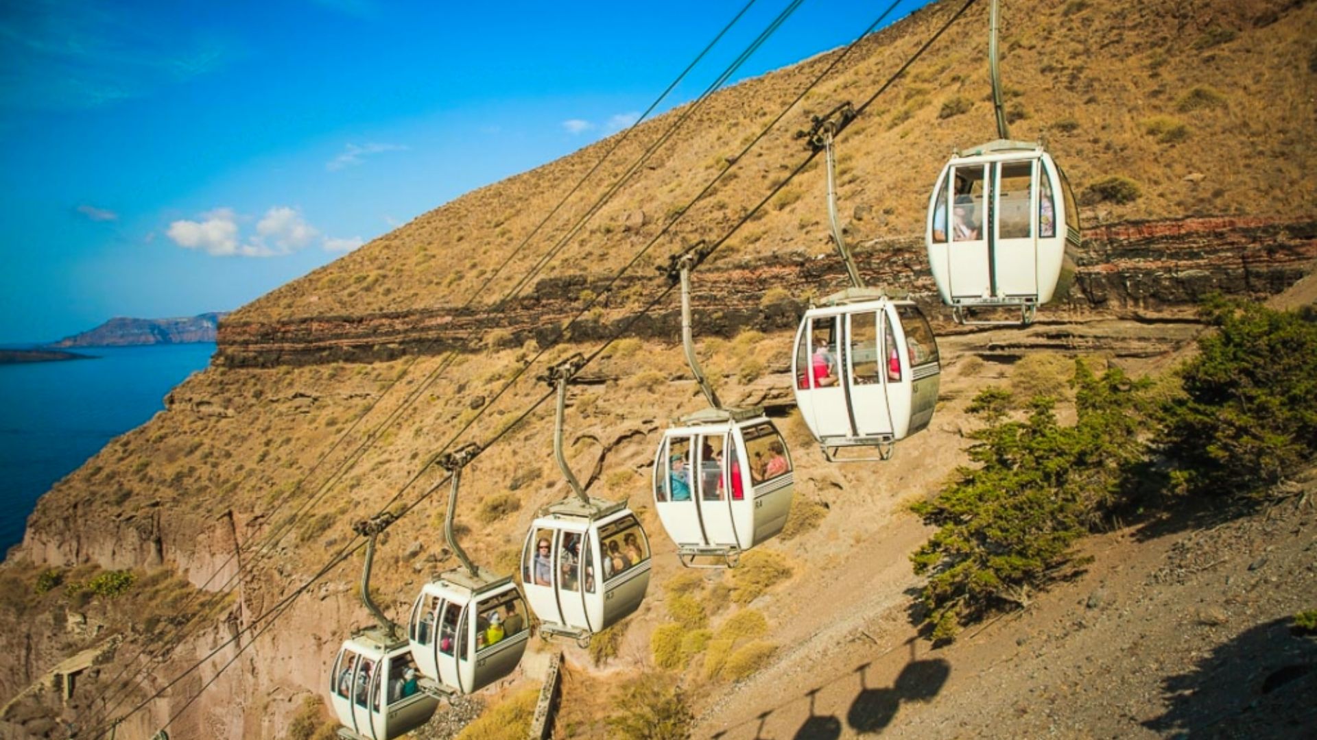 A cable car ascending the cliffs of Santorini, Greece, with stunning views of the island's landscape and sea.