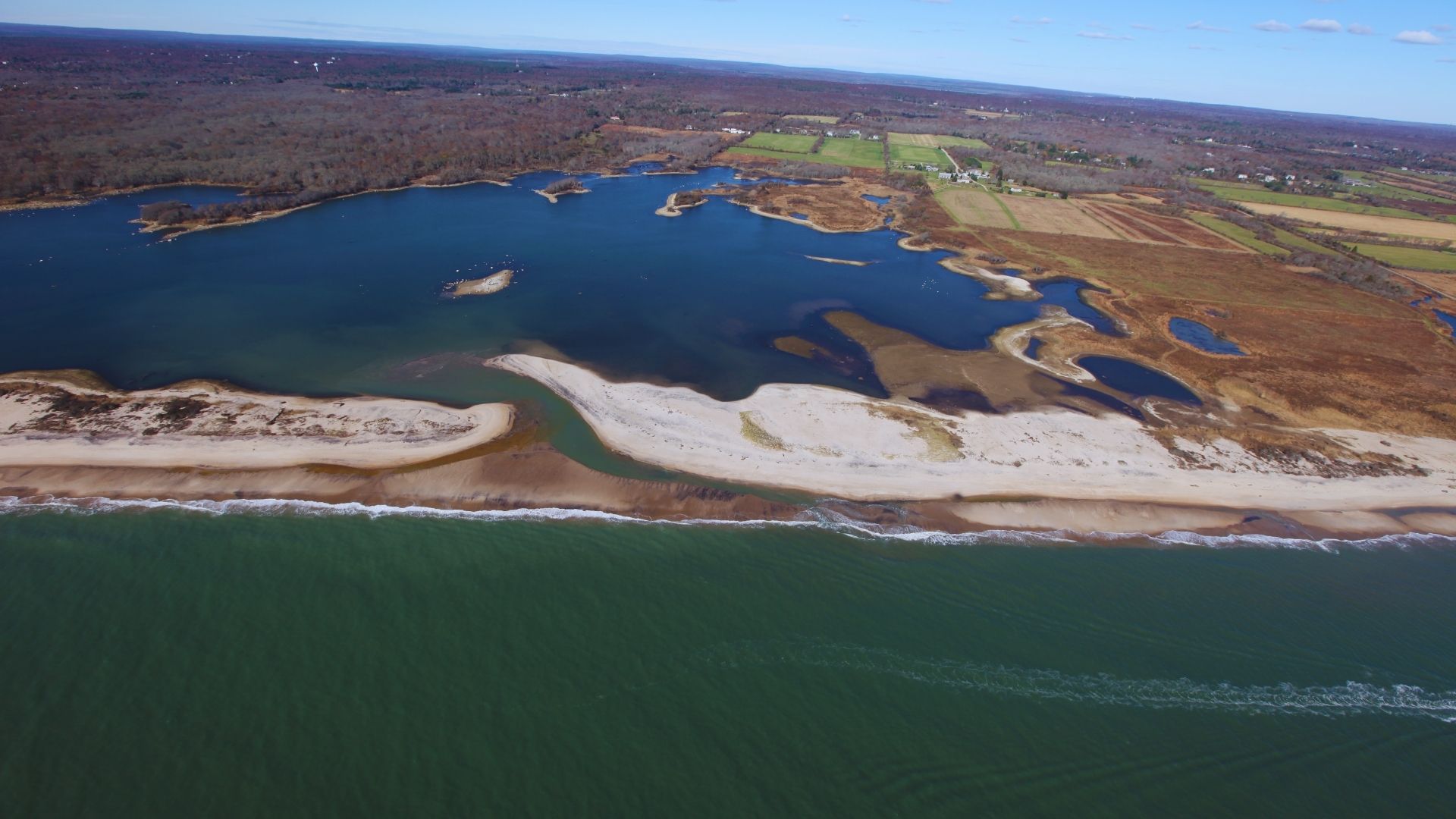 Aerial view of a sandy beach meeting turquoise water under a clear blue sky.