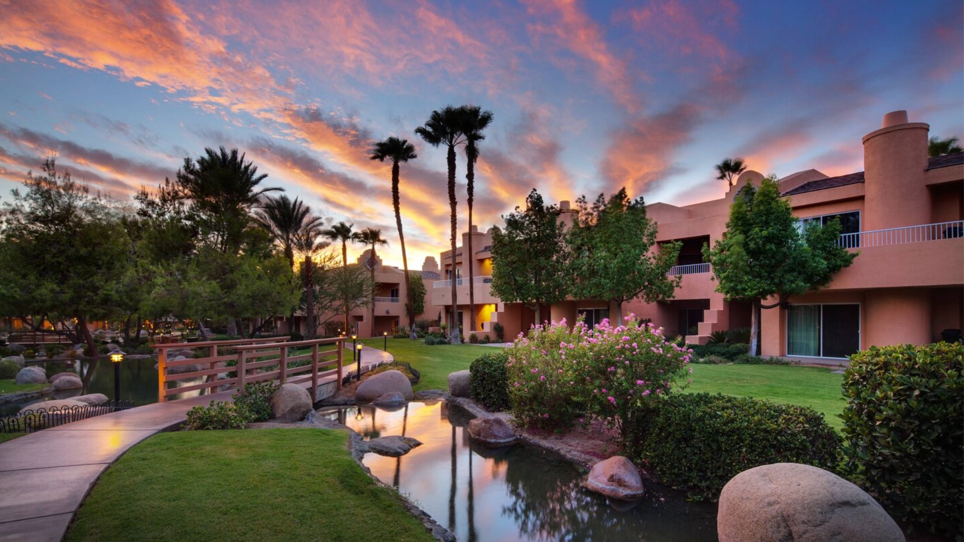 Sunset view of a Scottsdale, AZ resort, showcasing vibrant colors in the sky and silhouettes of palm trees.
