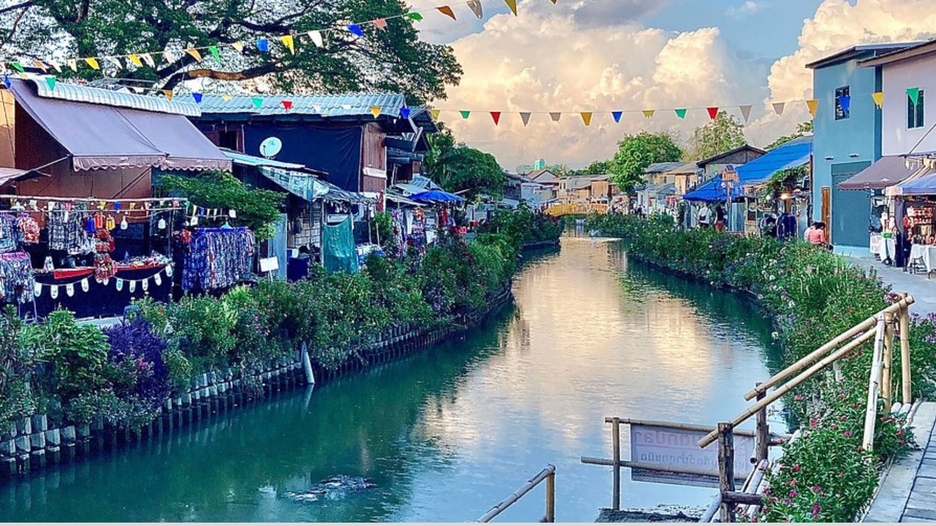 A scenic canal lined with shops, featuring people strolling along the walkway beside the water.
