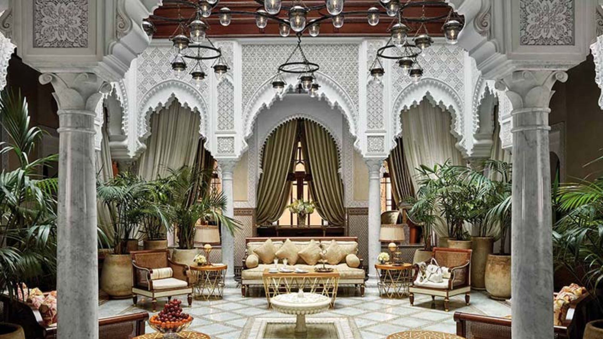 The elegant lobby of Riad Marrakech, featuring intricate tile work, lush plants, and traditional Moroccan decor.