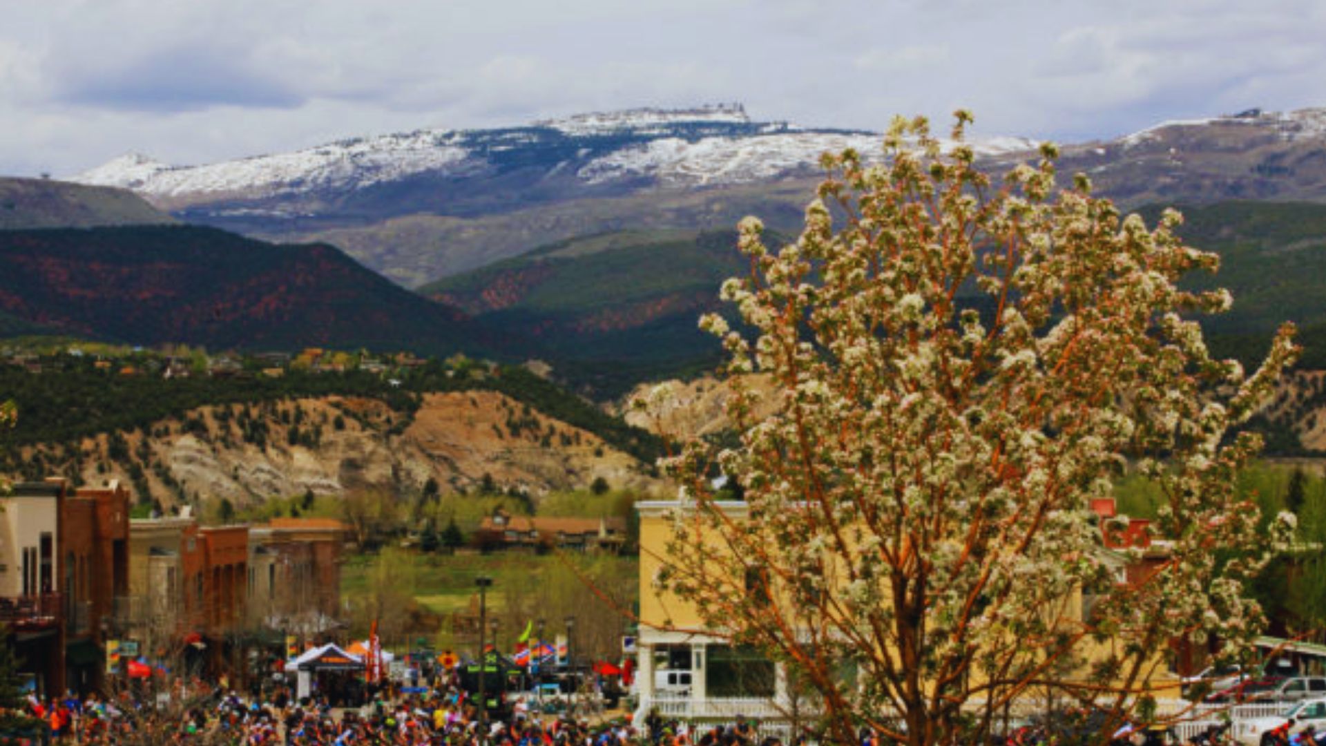 A diverse crowd of people gathers around a majestic mountain, enjoying the scenic view and each other's company.