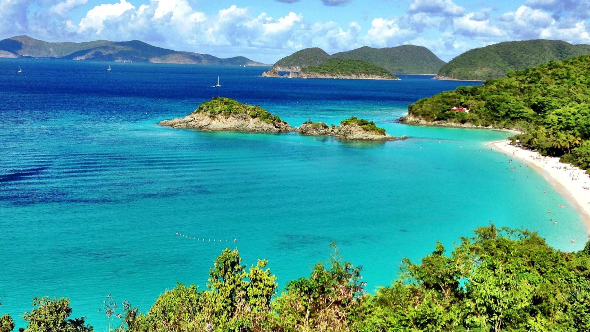 Pristine beaches of the Virgin Islands with soft white sand and clear turquoise waters under a bright blue sky.