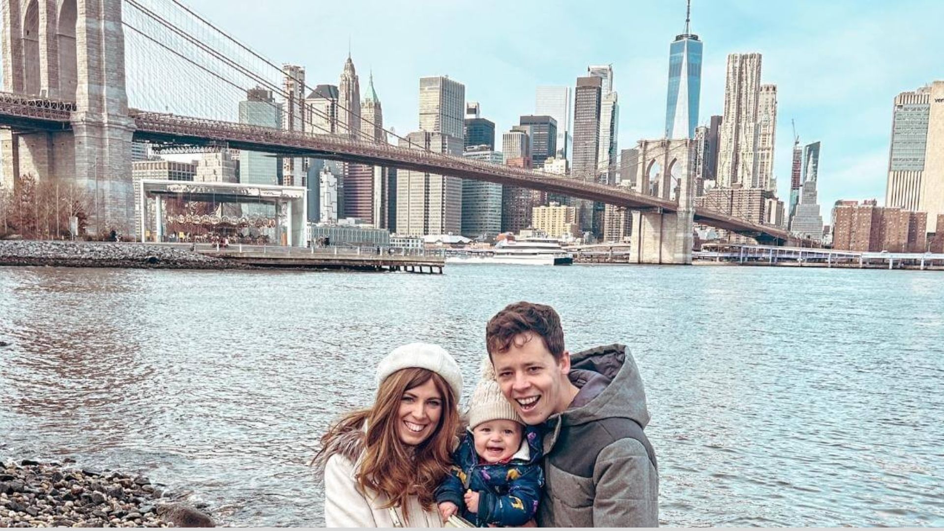 A family stands together, posing happily in front of the Brooklyn Bridge, showcasing the landmark in the background.