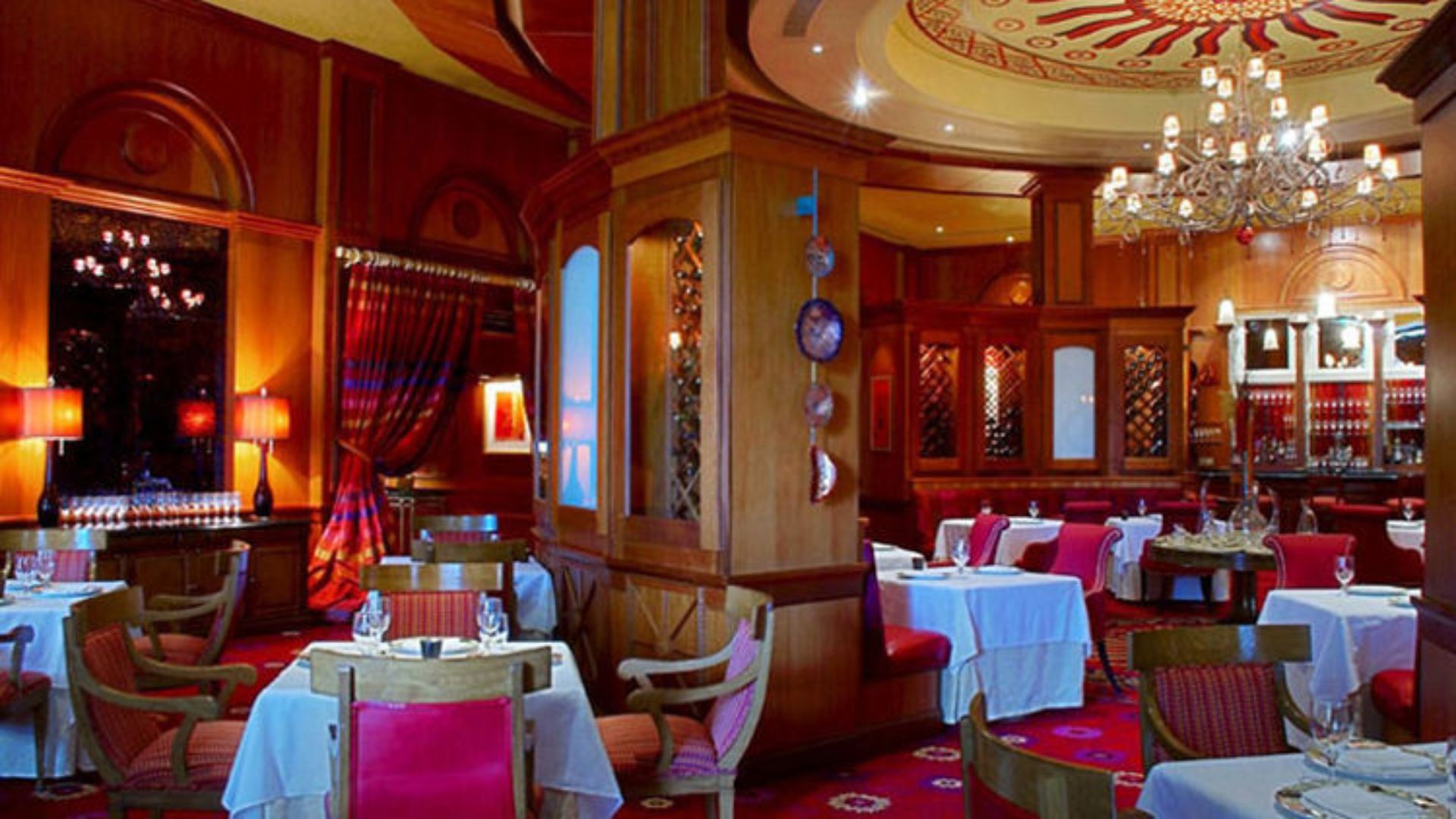Elegant restaurant interior featuring a red carpet and a sparkling chandelier overhead.