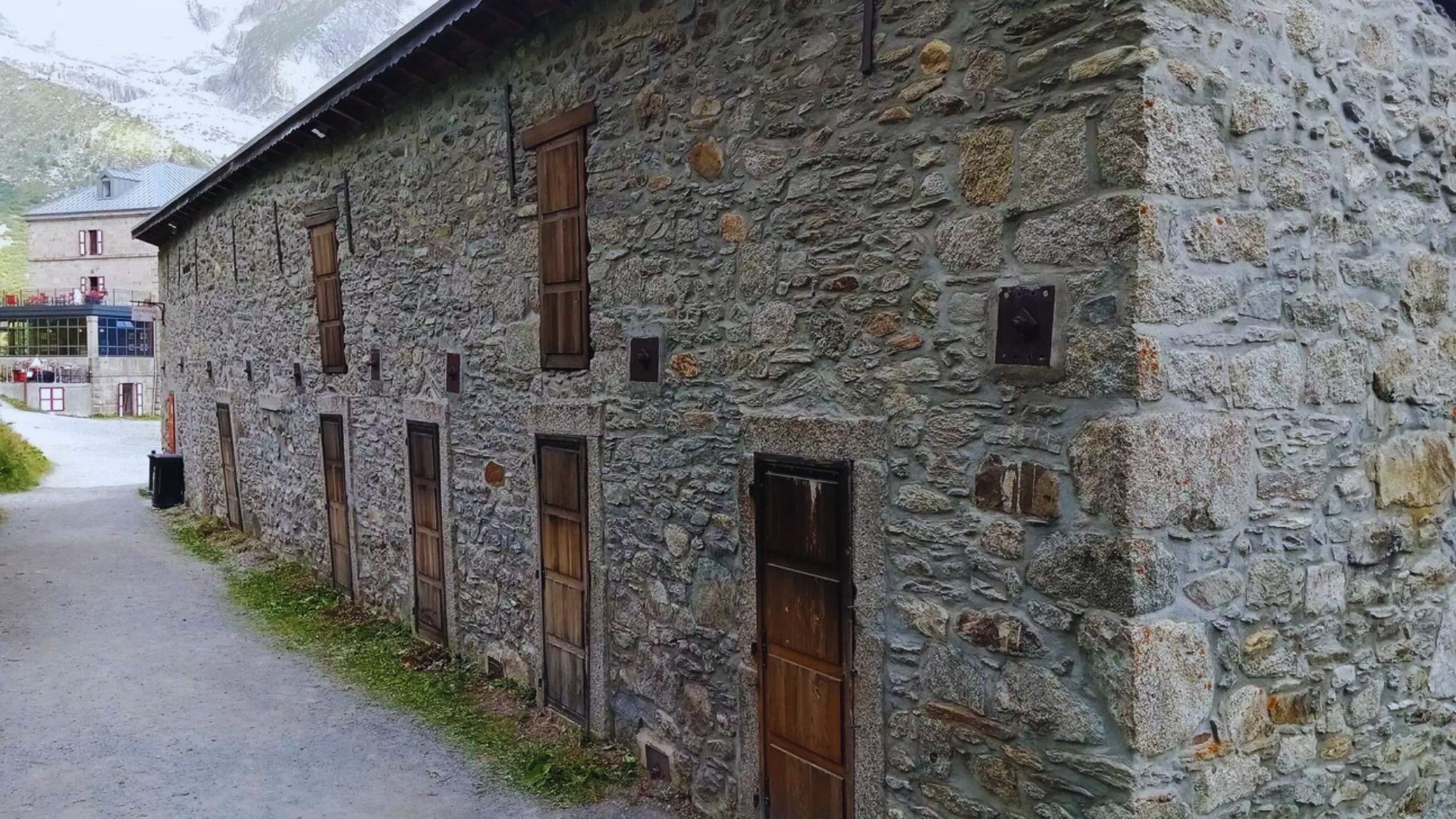 A stone building featuring wooden doors and windows, showcasing a rustic architectural style.