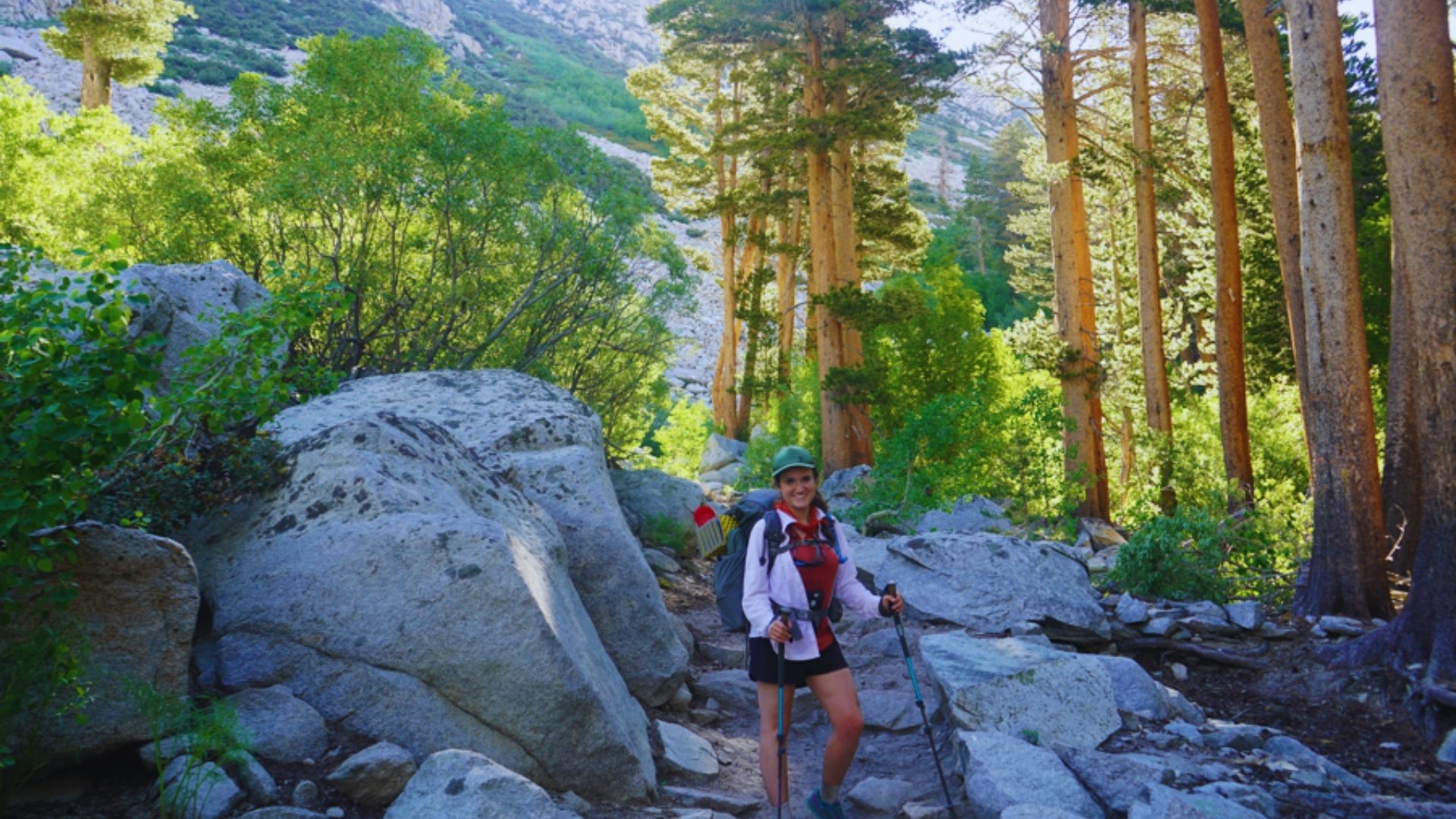 A hiker navigating a rocky mountain trail, surrounded by rugged terrain and distant peaks.