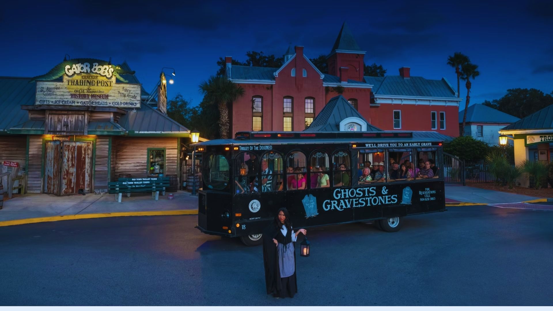 A black trolley parked on the side of the road with several people standing nearby, waiting to board.