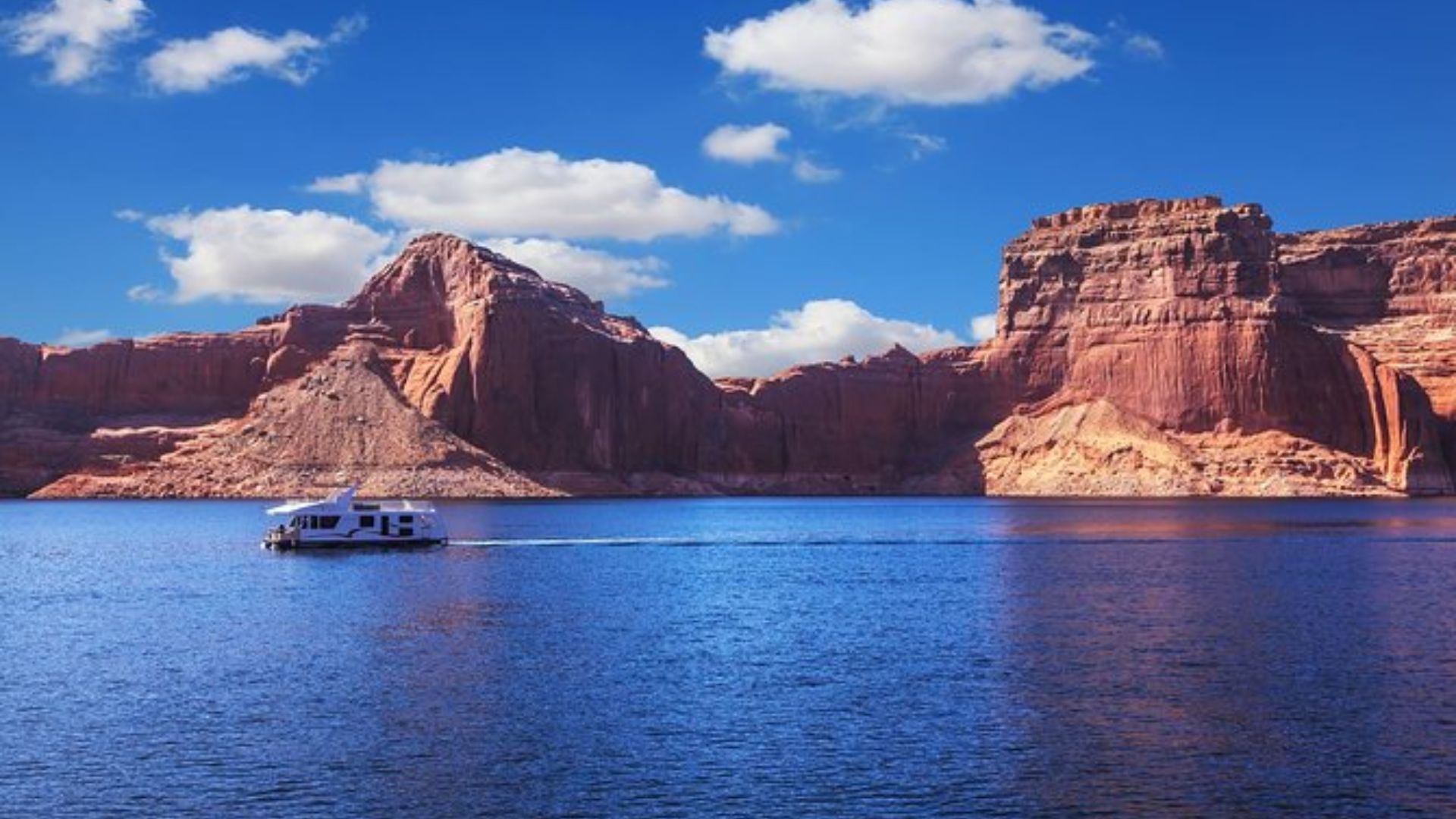 A boat glides through water, with a majestic mountain rising in the background.