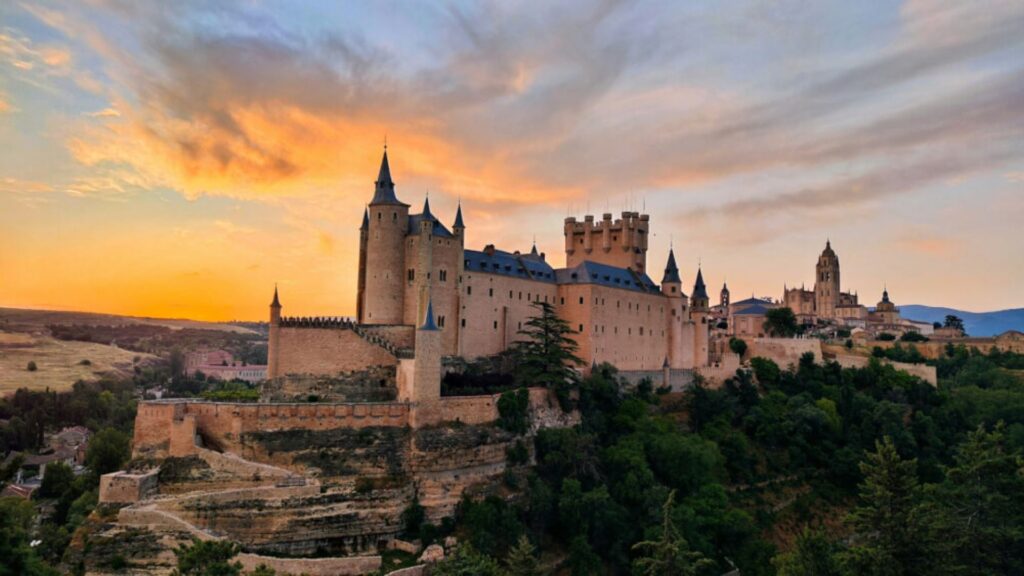 Alcaz Castle in Alcaz, Spain, silhouetted against a vibrant sunset sky, highlighting its historic architecture.