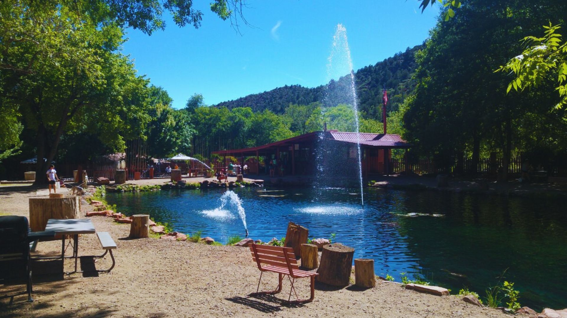 1. A serene pond featuring a fountain, surrounded by picnic tables for outdoor gatherings.