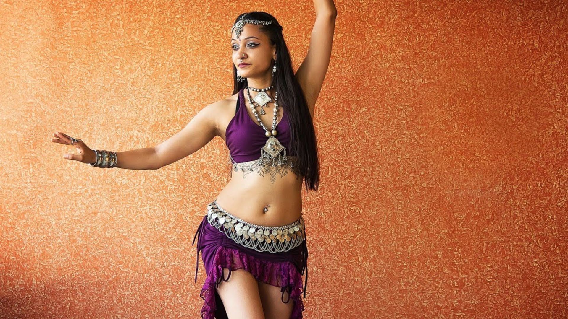 A woman wearing a colorful belly dance outfit, showcasing intricate patterns and flowing fabric.