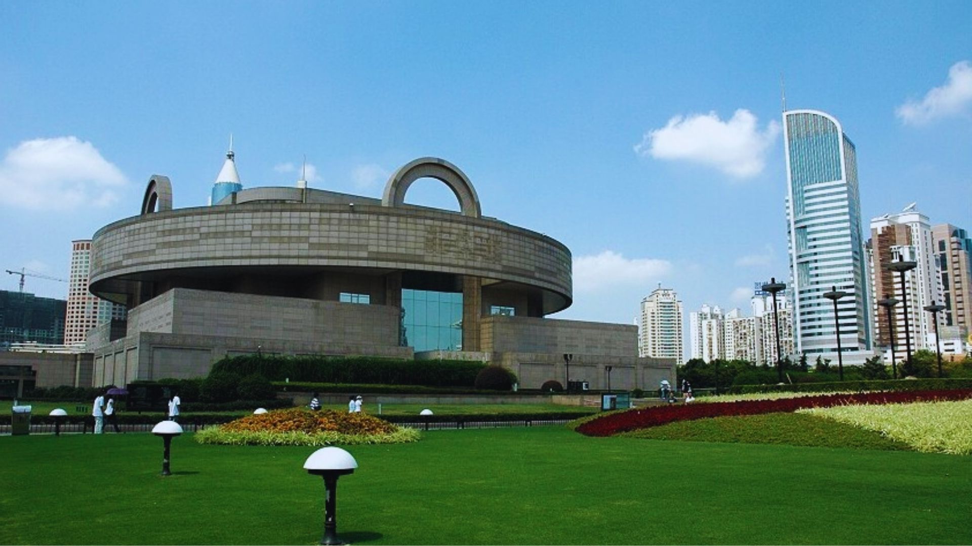 A large building stands behind a circular lawn, creating a spacious and inviting outdoor area in front of it.