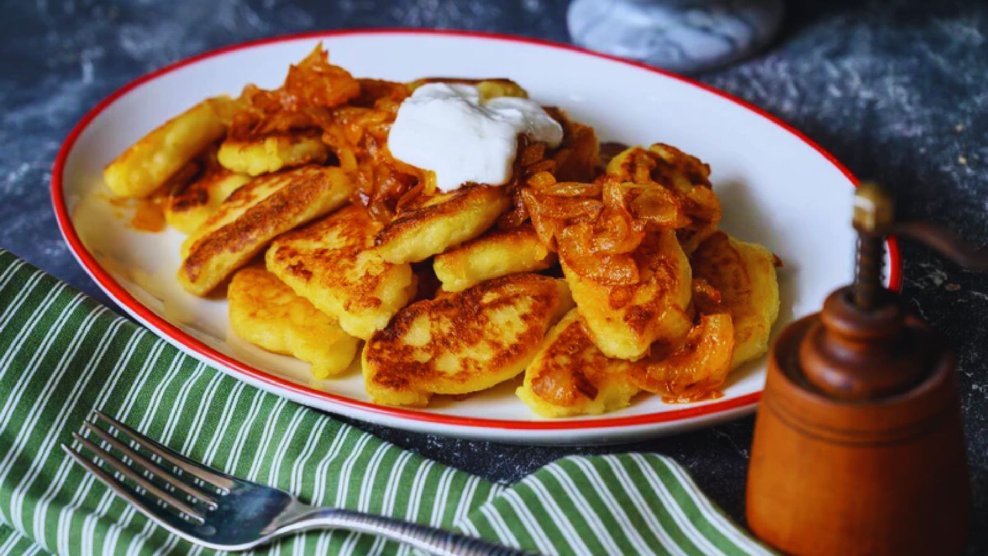 A plate of food featuring creamy mashed potatoes topped with a dollop of sour cream.