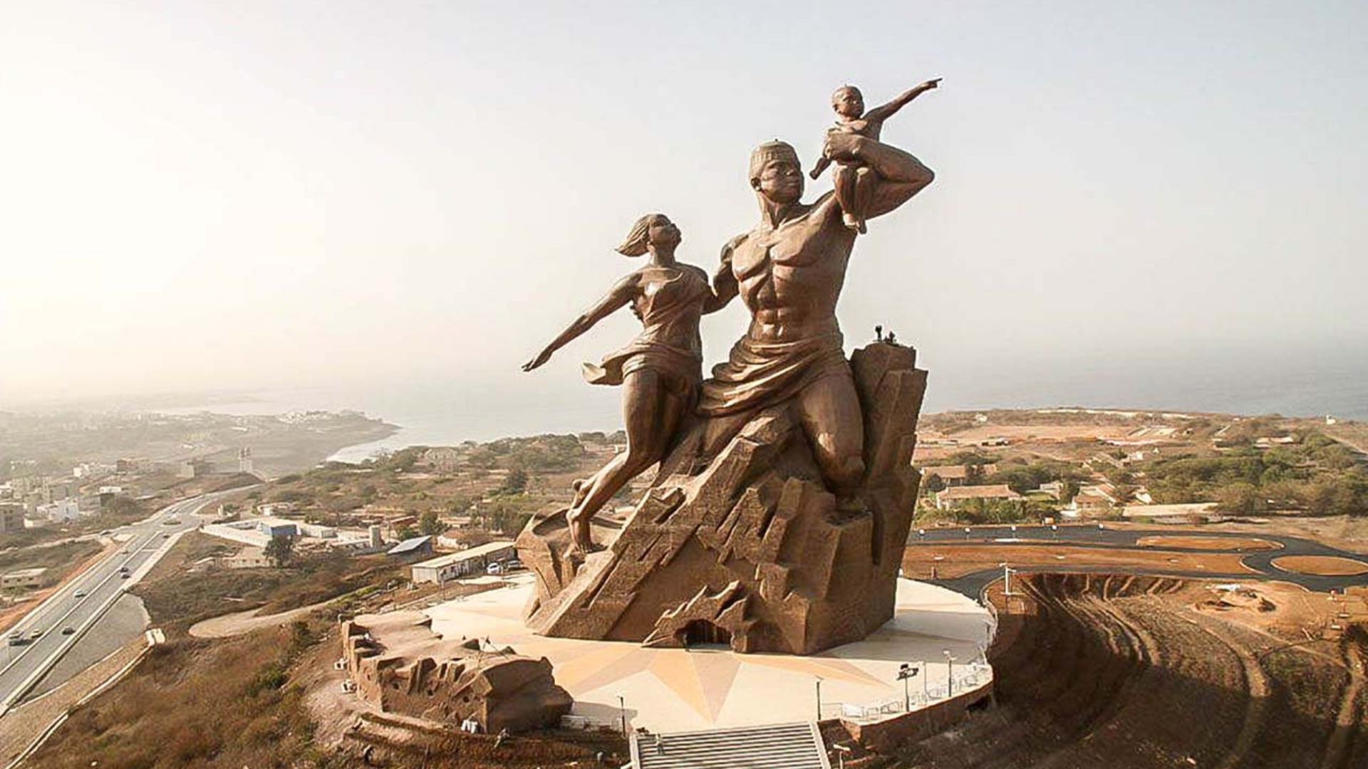 A statue of two figures standing together on a hill, overlooking the landscape below.