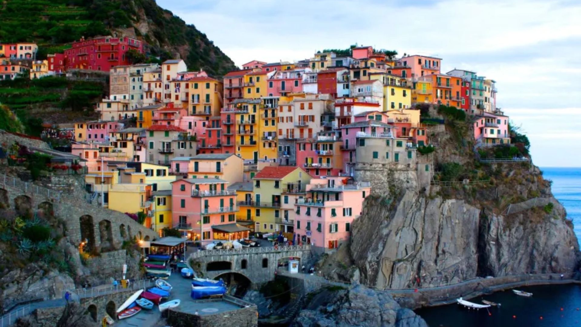 Colorful houses perched on a cliff, overlooking a vast ocean under a clear blue sky.