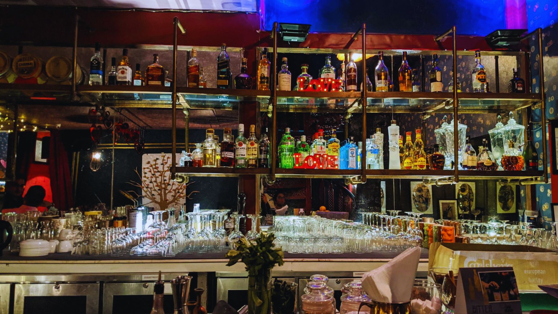 A well-stocked bar featuring numerous bottles and glasses neatly arranged on the shelves.