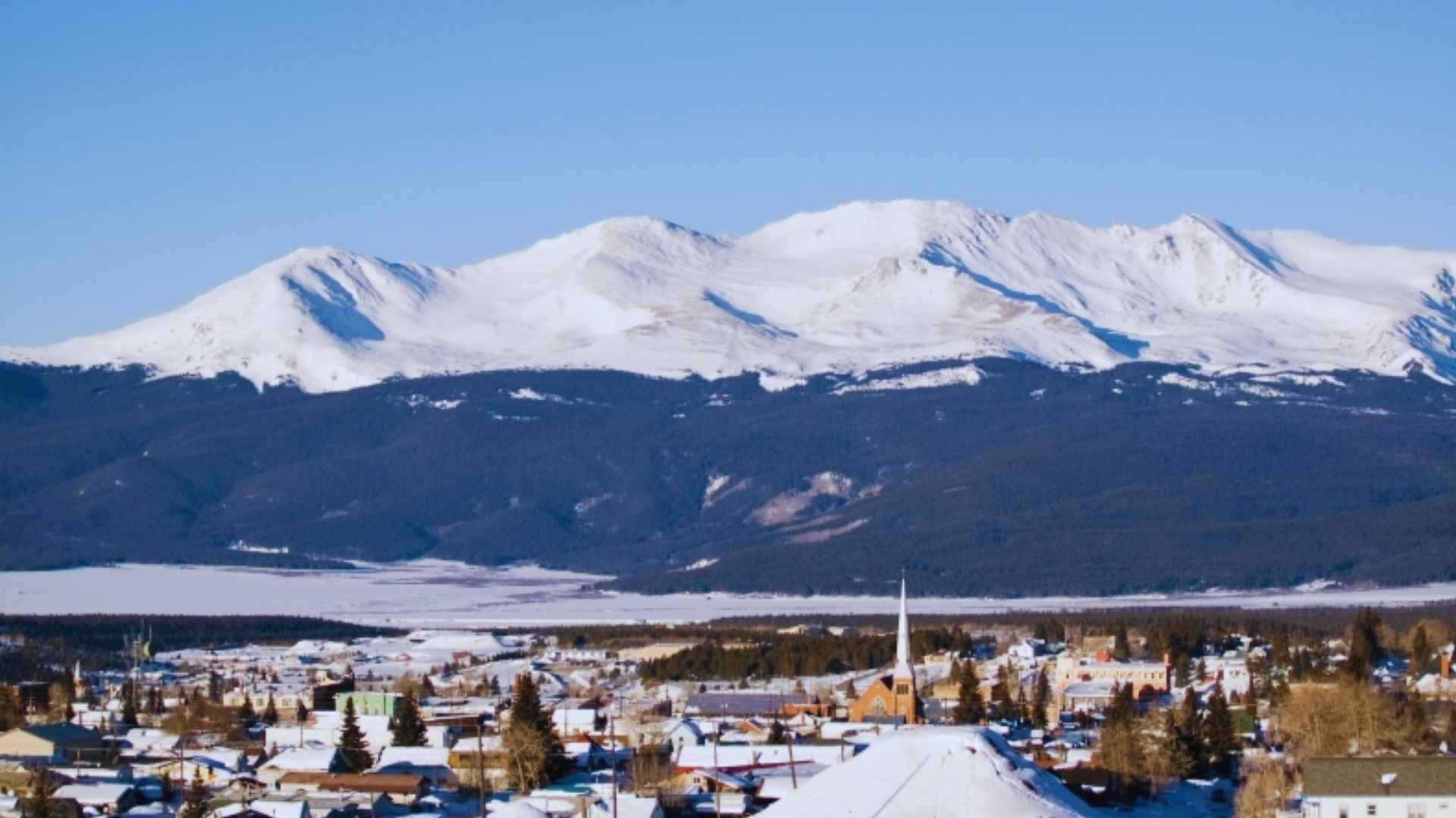 A picturesque town with snow-capped mountains rising majestically in the background.
