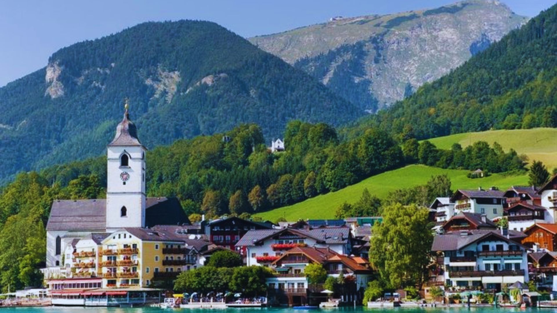 A picturesque town by the lake, surrounded by majestic mountains in the background.
