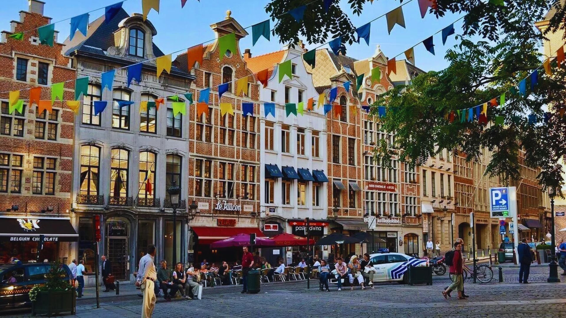 A vibrant city street adorned with colorful flags hanging from buildings, creating a festive atmosphere.